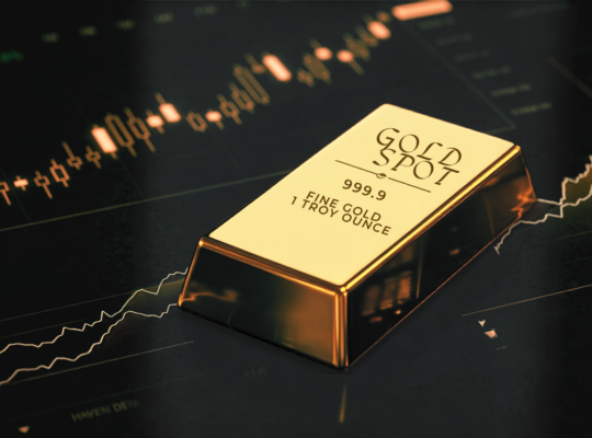 Polished gold spot bullion bar on a dark surface with glowing financial stock market candlestick charts and price metrics.
